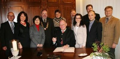 MdL Franz Maget (sitzend) trägt sich ins Goldene Buch der Gemeinde ein