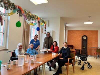 Sibylle Entwistle, Ruth Müller, MdL, und Johann Luger übergeben die Krapfen Ashley Cassada (in blau) und di